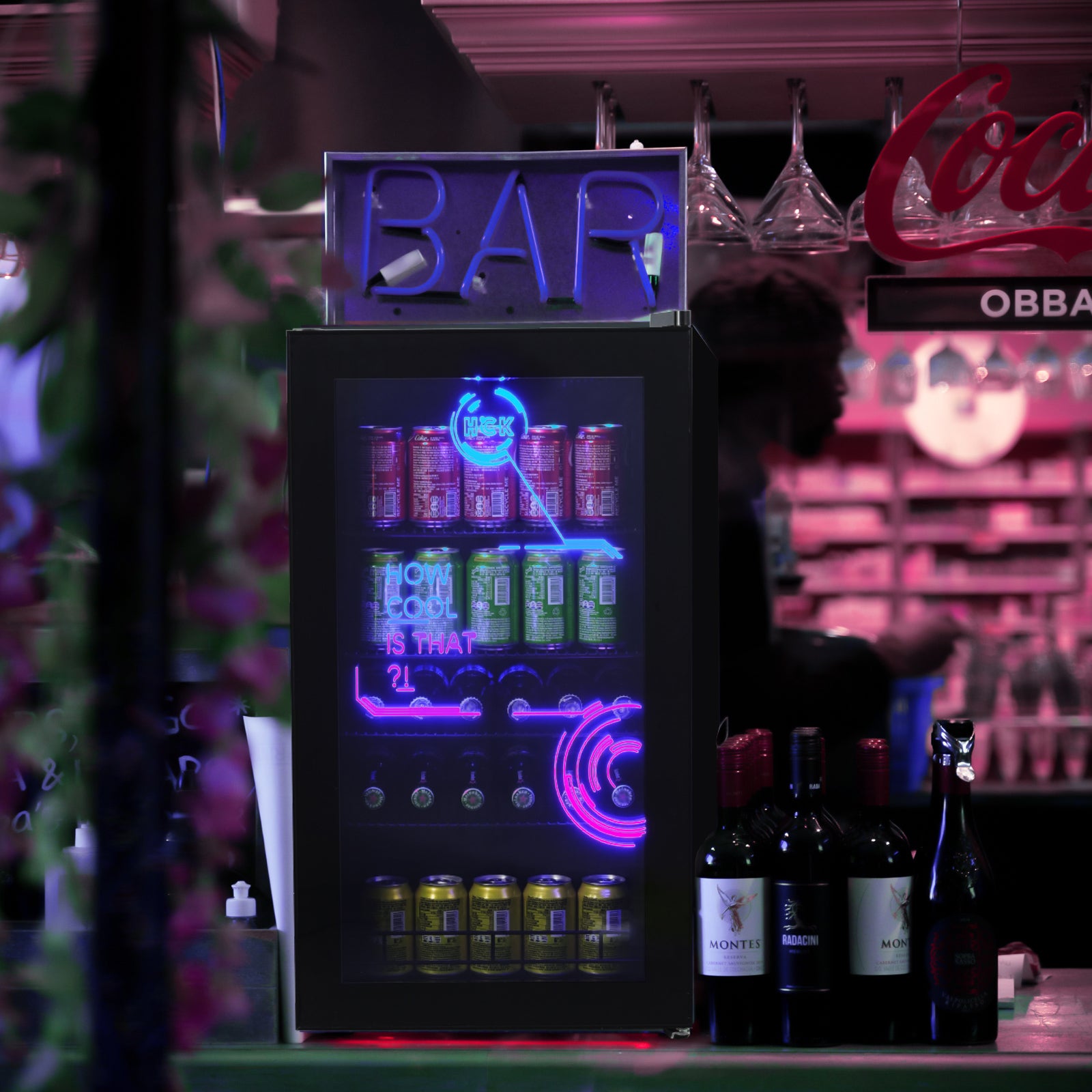 A 3.5 Cu Ft Cyberpunk Glass Door Beverage Fridge placed in a bar setup, positioned on a table beside bottles of wine